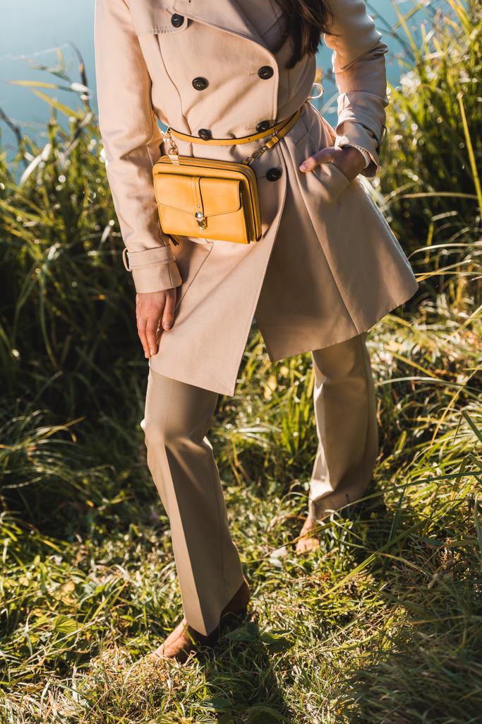 imagem cortada de mulher na moda em casaco posando com saco amarelo ao ar livre
  - Foto, Imagem