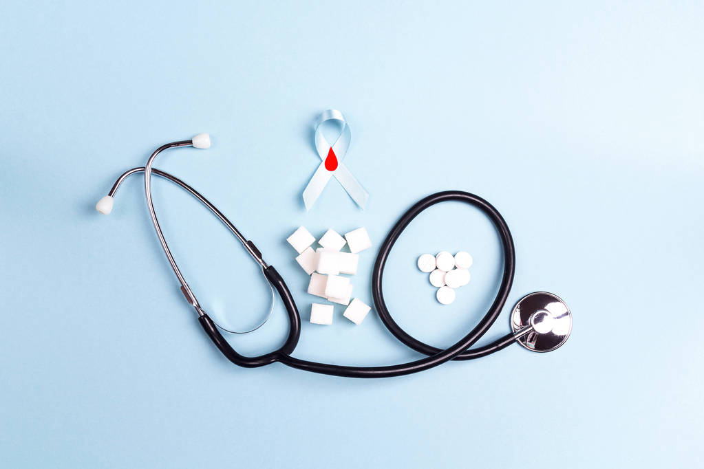 blaues Band mit Stethoskop, raffiniertem Zucker und Tabletten auf blauem Hintergrund. Konzept zum Weltdiabetestag. - Foto, Bild
