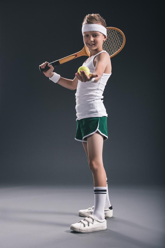 menino sorridente em sportswear com raquete de tênis e bola no fundo escuro
 - Foto, Imagem