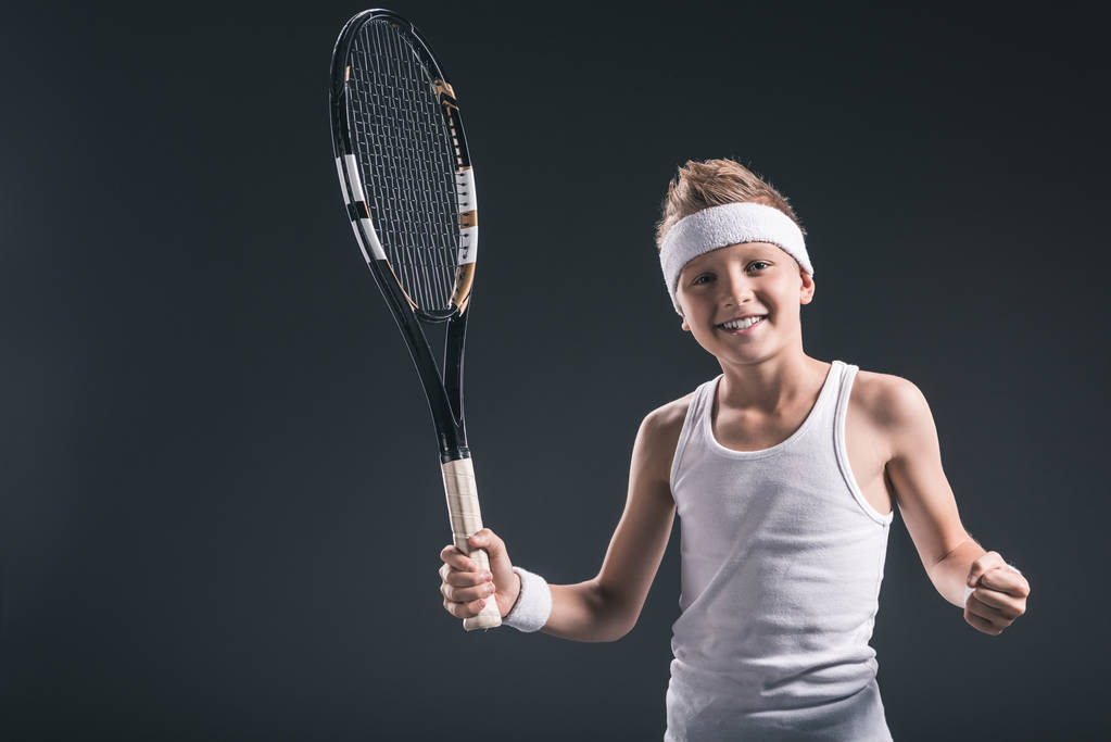 暗い背景上のテニス ラケット スポーツ ウエアで微笑む少年の肖像画 - 写真・画像