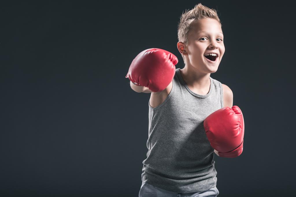 портрет веселого мальчика в красных боксёрских перчатках на черном фоне
 - Фото, изображение