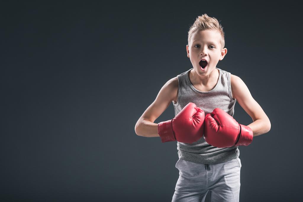 retrato de niño emocional con guantes de boxeo rojos sobre fondo negro
 - Foto, imagen