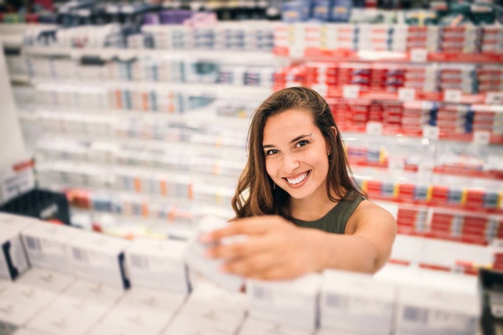 Giovane donna che tiene i cosmetici in mano nel supermercato
. - Foto, immagini