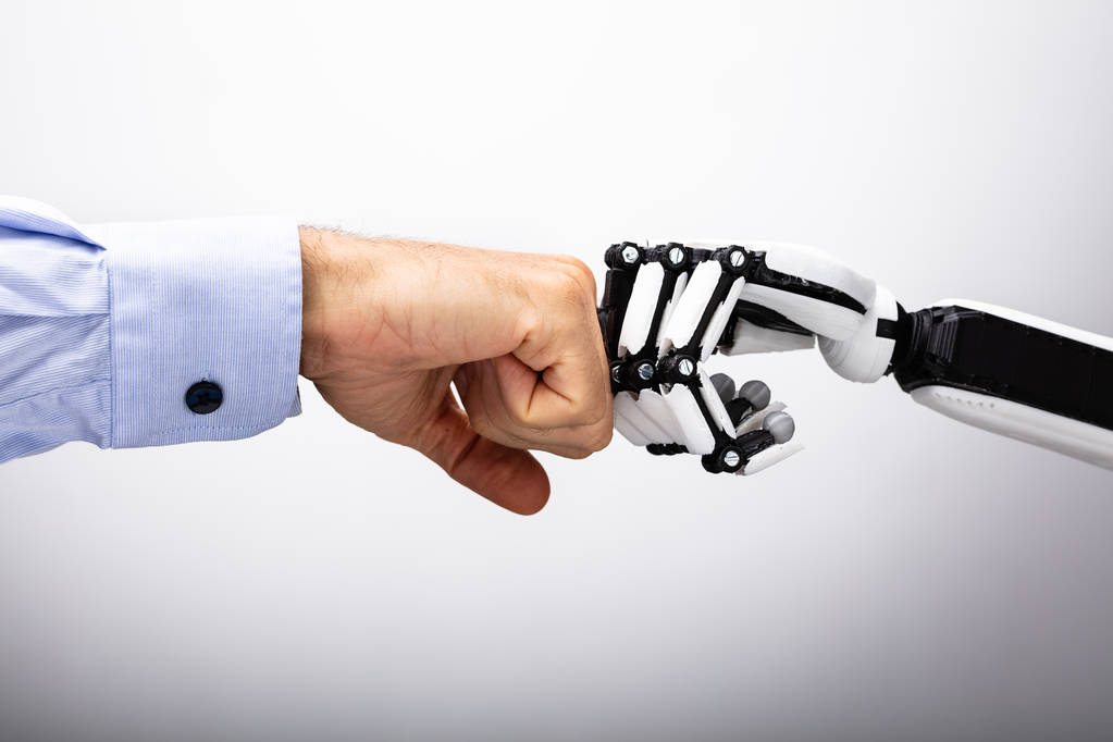 Ανθρώπινο χέρι και ρομπότ κάνοντας γροθιά χτύπημα σε γκρίζο φόντο - Φωτογραφία, εικόνα