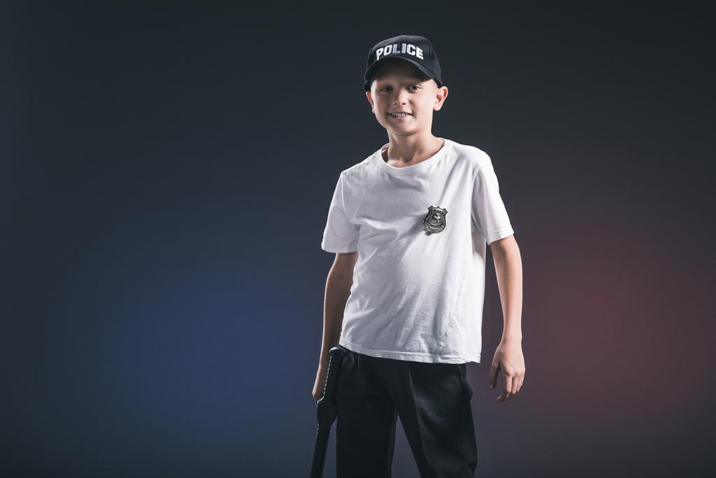 portrait of preteen boy in white tshirt and cap police officer uniform in dark backdrop - Photo, Image