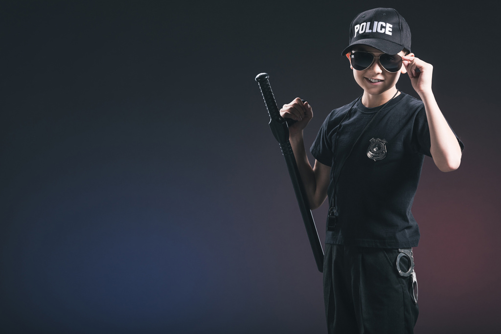 retrato de menino no uniforme policial e óculos de sol no fundo escuro
 - Foto, Imagem