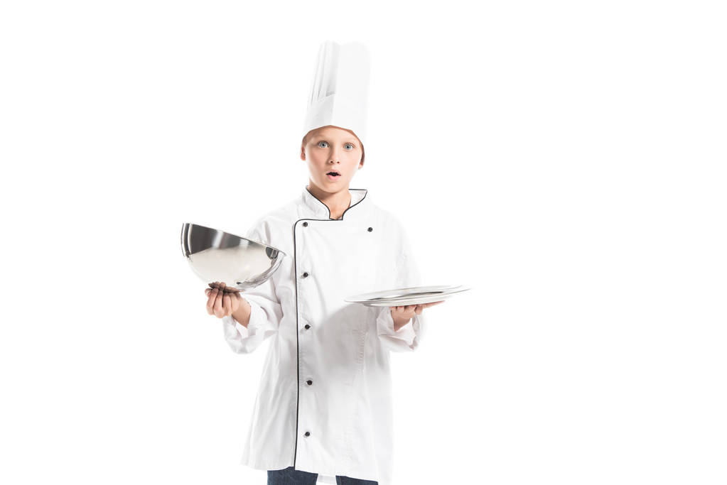 shocked boy in chef uniform and hat holding empty serving tray isolated on white - Photo, Image