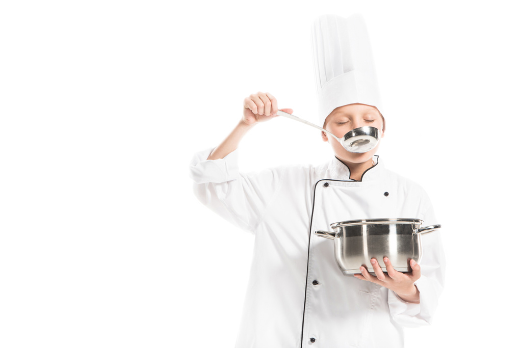 pre-adolescente jongen in chef-kok uniform met steelpan en pollepel geïsoleerd op wit - Foto, afbeelding