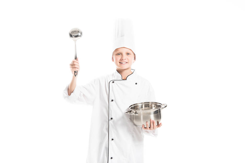 Vorpubertärer Junge in Kochuniform mit Topf und Schöpfkelle isoliert auf weiß - Foto, Bild