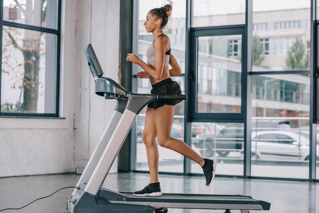 side view of african american sportswoman running on treadmill at gym - Photo, Image