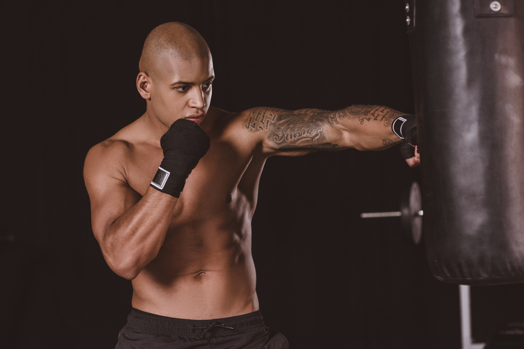 Tetovaný afroamerické pejsek boxer v boxu obvaz školení s boxovací pytel v tělocvičně - Fotografie, Obrázek