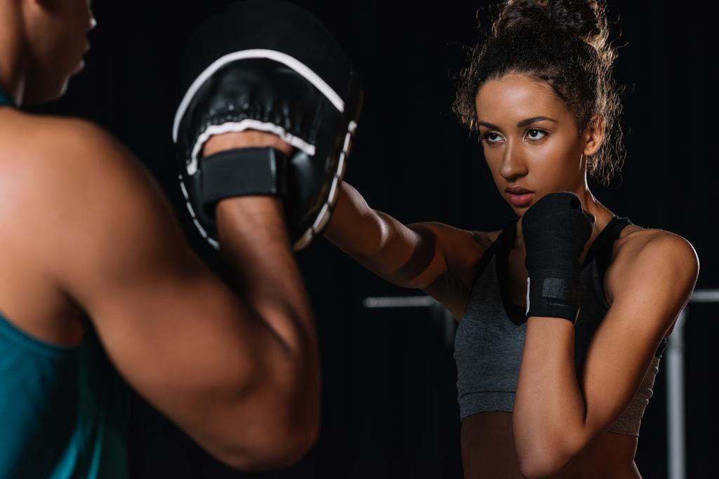 gedeeltelijke weergave van mannelijke persoonlijke trainer trainen met de vrouwelijke bokser op sportschool - Foto, afbeelding