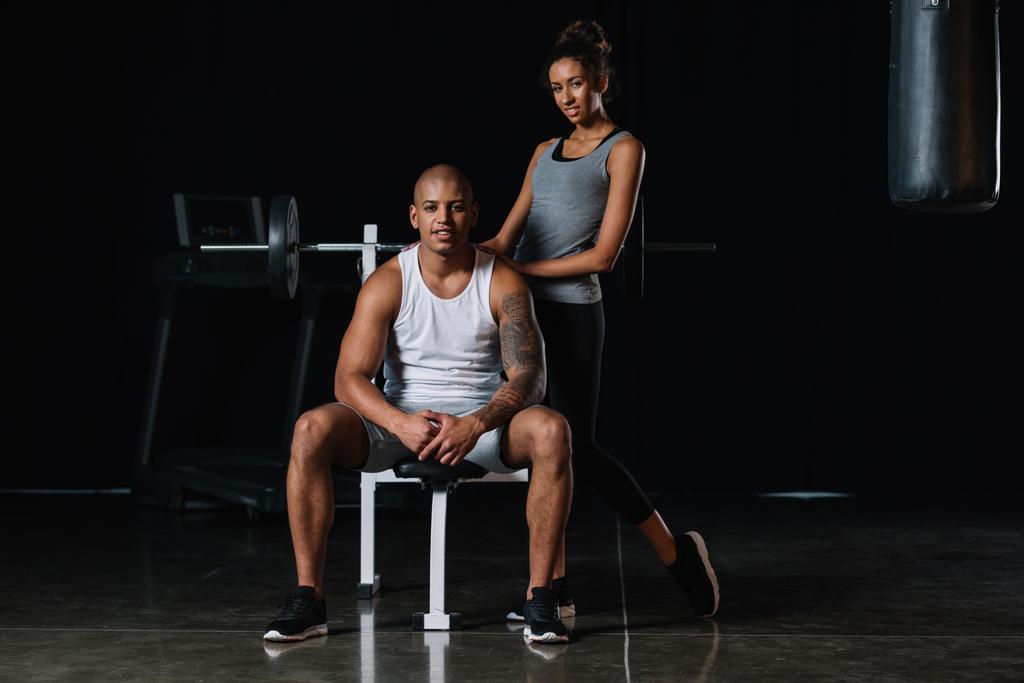 attraente donna sportiva africana americana in piedi vicino al fidanzato muscolare in palestra
 - Foto, immagini