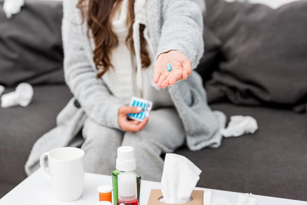 cropped shot of sick woman in warm clothes holding pill in hand - Photo, Image