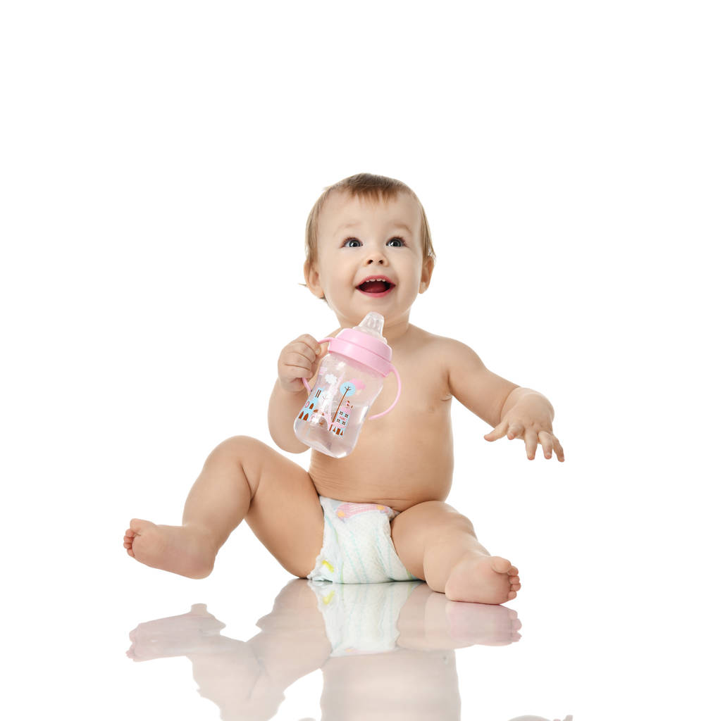 幼児女の子幼児ホールド飲む哺乳瓶を見て笑みを浮かべて幸せ  - 写真・画像