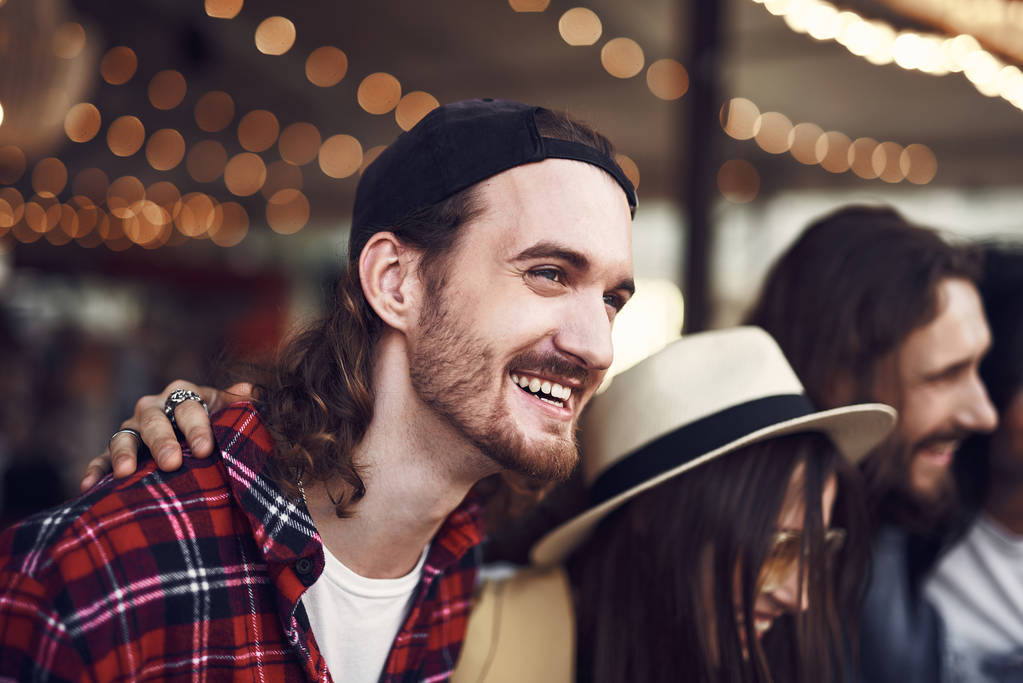 Feliz hombre barbudo riendo mientras está de pie con amigos al aire libre
 - Foto, Imagen