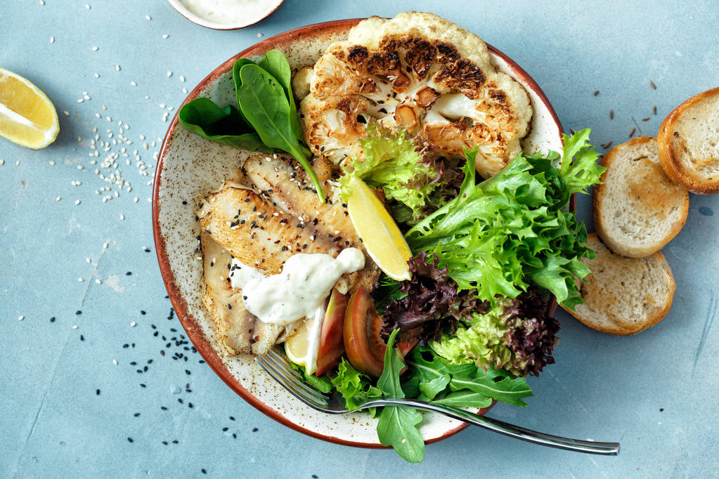 Vista superior concepto de alimentos sanos limpios y equilibrados. Almuerzo saludable. Filete de pescado frito, verduras y lechuga sobre fondo azul piedra
 - Foto, imagen