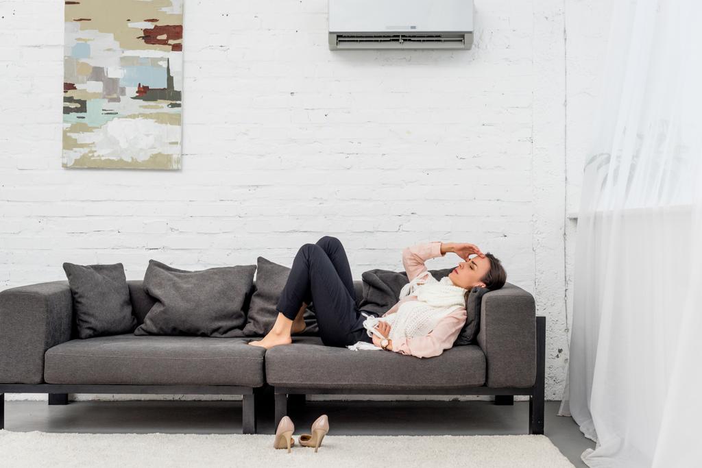 вид збоку хворої молодої жінки, що лежить на дивані під кондиціонером вдома
 - Фото, зображення