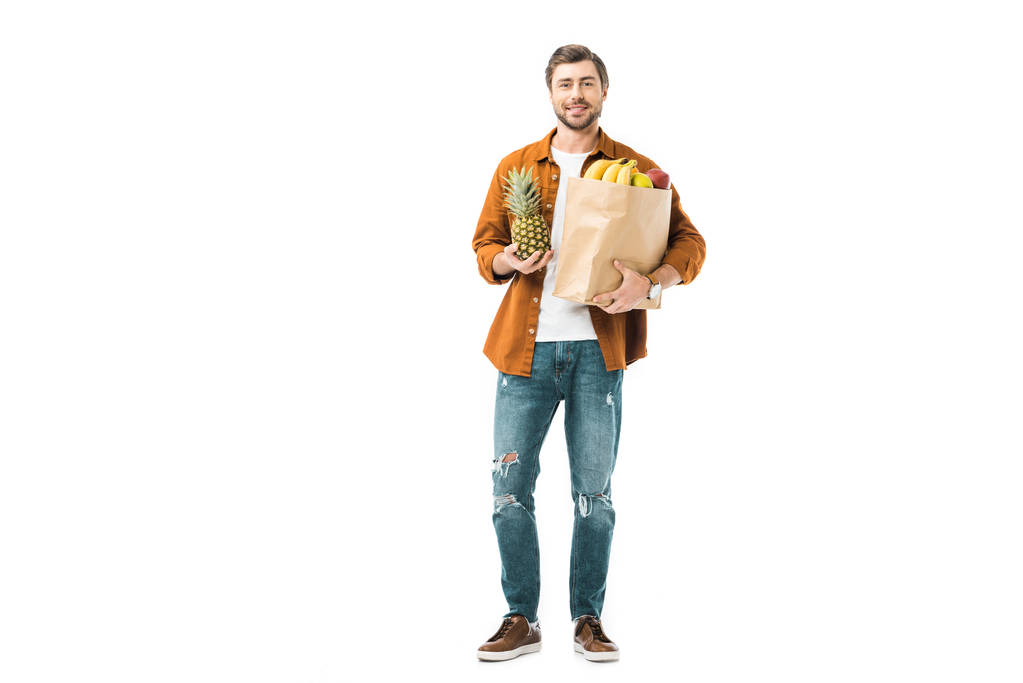 uomo con ananas e sacchetto di carta pieno di prodotti isolati su bianco
 - Foto, immagini
