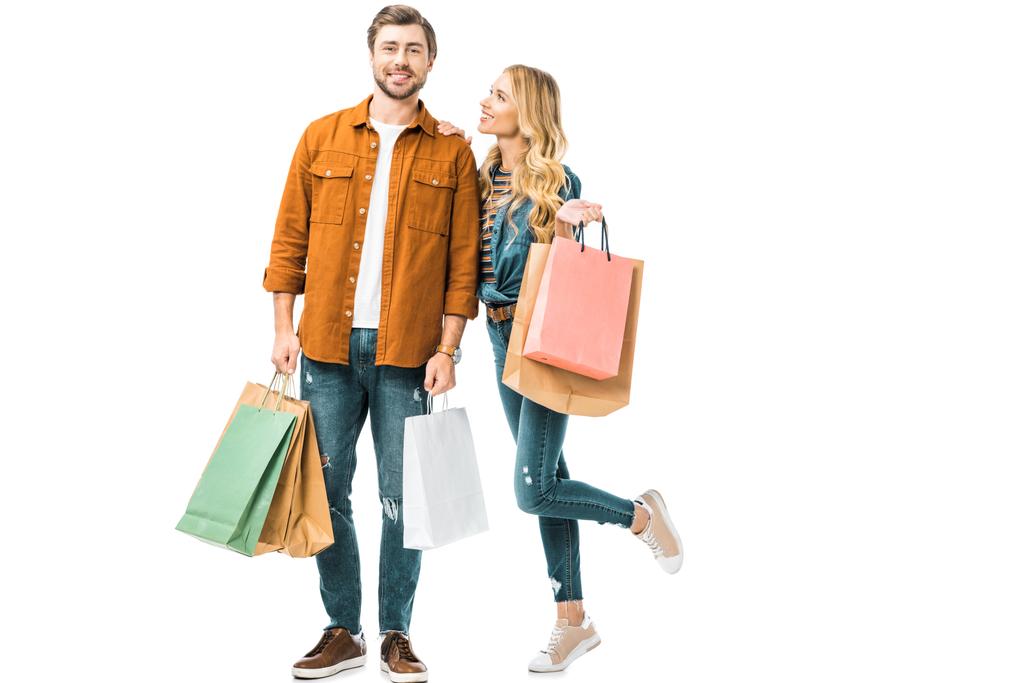 feliz pareja joven sosteniendo coloridas bolsas de compras aisladas en blanco
 - Foto, imagen
