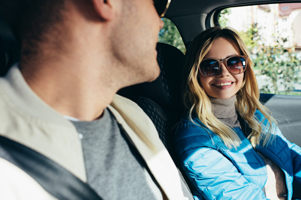 hymyilevä nainen aurinkolaseissa katsomassa poikaystävää autossa
 - Valokuva, kuva