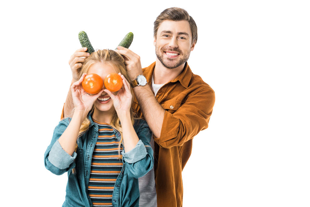 homme gai faire des cornes avec des concombres à petite amie alors qu'elle couvre les yeux par des tomates isolées sur blanc
 - Photo, image