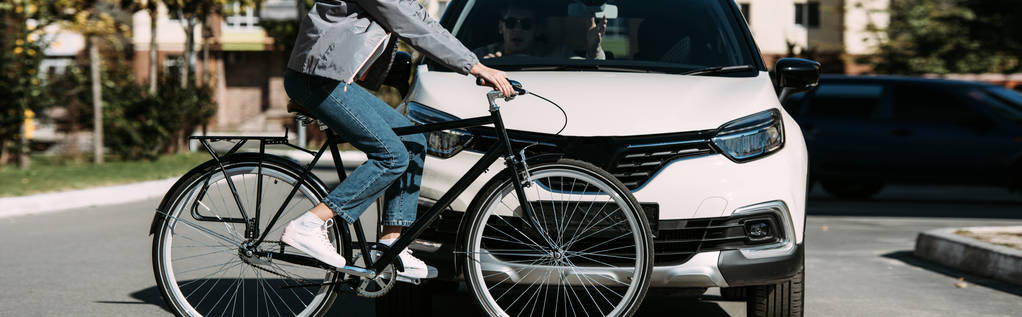 Teilansicht einer Radfahrerin beim Überqueren der Straße mit Fahrer im Auto - Foto, Bild