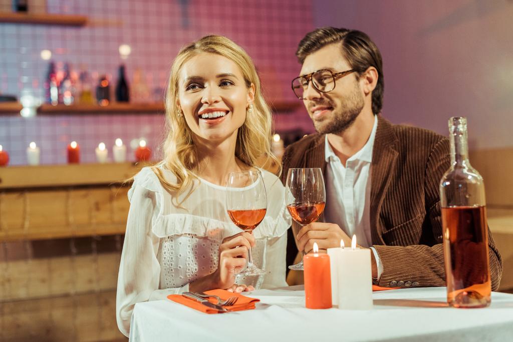 junges Paar mit Weingläsern feiert Date am Tisch mit Kerzen im Restaurant  - Foto, Bild