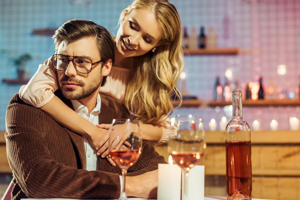 красивая молодая женщина обнимает расстроенного парня во время романтического ужина за столом в ресторане
  - Фото, изображение