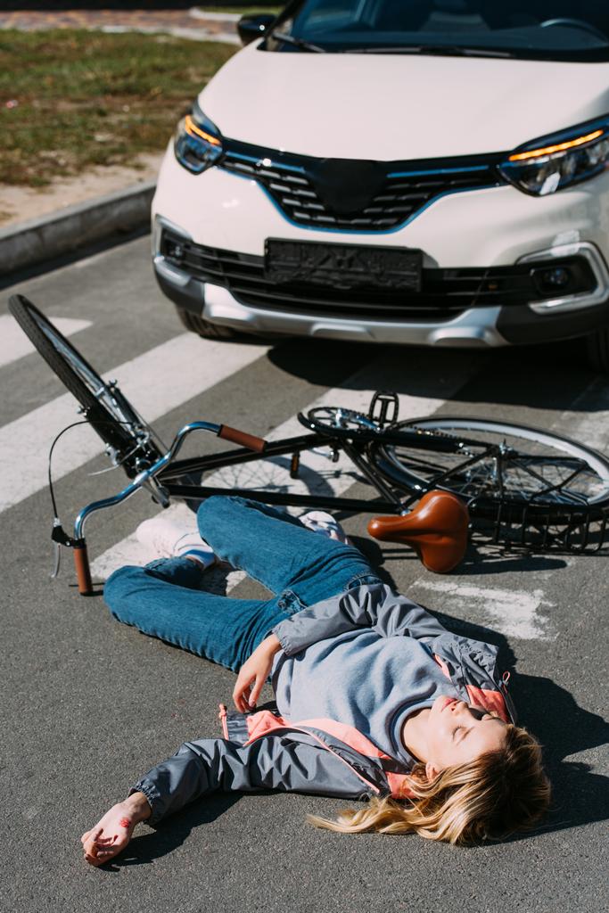 若い女性に行く道路、車事故概念で自転車を運転している間ダウン車で刈られました。 - 写真・画像