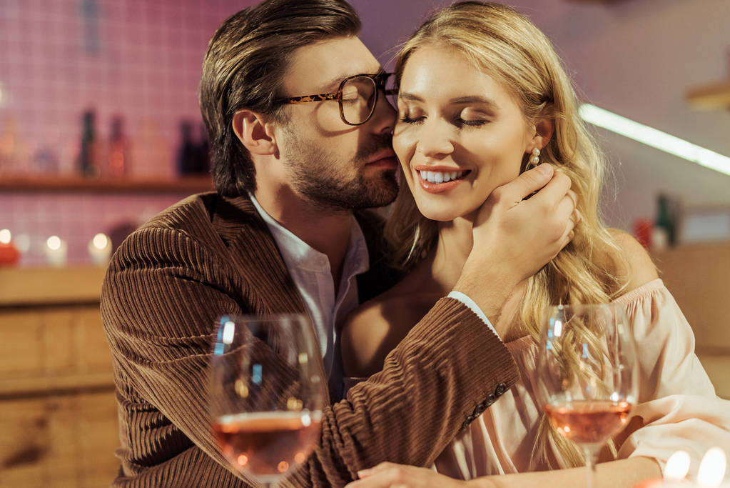 Μερική άποψη του νεαρού σακάκι φιλιά όμορφη κοπέλα κατά τη διάρκεια ρομαντικό δείπνο στο εστιατόριο  - Φωτογραφία, εικόνα