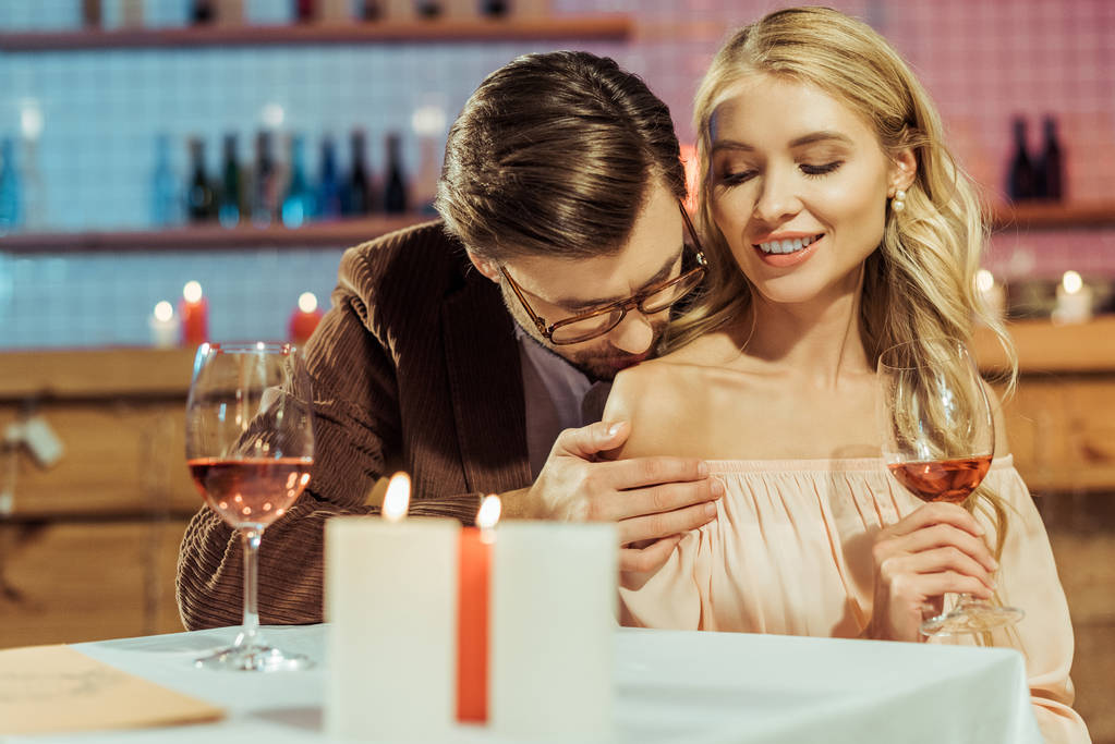 κομψό άνδρα στο σακάκι φιλιά όμορφη κοπέλα κατά τη διάρκεια ρομαντικό δείπνο στο εστιατόριο  - Φωτογραφία, εικόνα