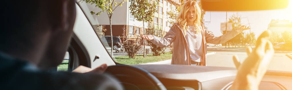 Молодая женщина ссорится с водителем автомобиля во время перехода дороги
 - Фото, изображение
