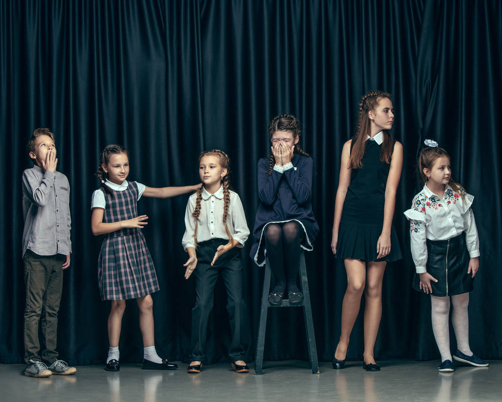 Roztomilý elegantní děti na pozadí tmavě studio. Krásné dospívající dívky a chlapci stáli - Fotografie, Obrázek