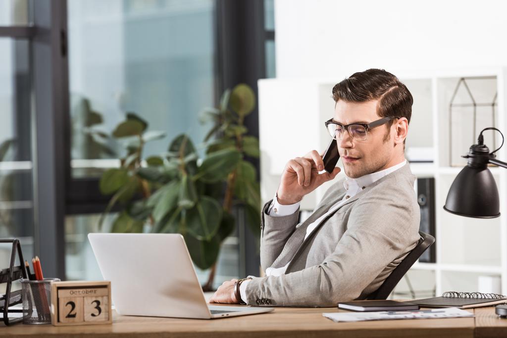 успішний впевнений бізнесмен розмовляє по телефону на робочому місці в офісі
 - Фото, зображення