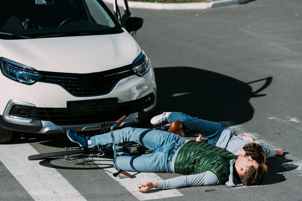 młodych rowerzystów leżącego na drodze o wypadku samochodowym - Zdjęcie, obraz