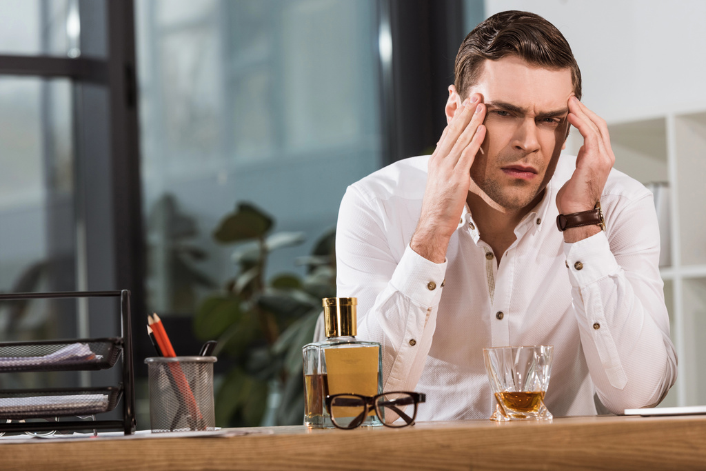 homme d'affaires déprimé avec un verre de whisky souffrant de maux de tête au bureau
 - Photo, image