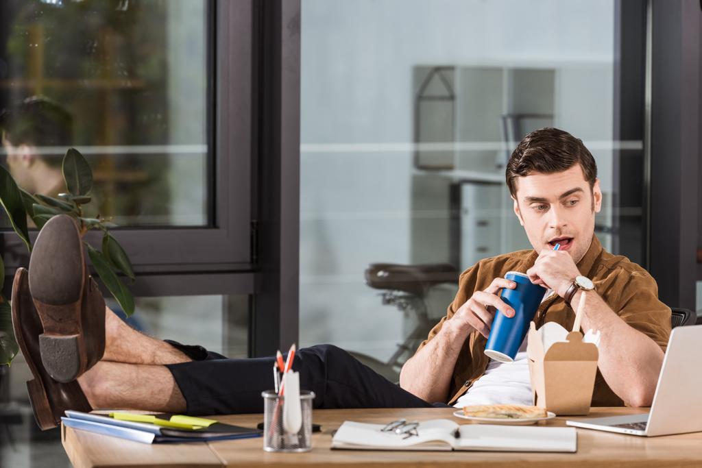 красивий бізнесмен обідає і п'є соду на робочому місці в офісі
 - Фото, зображення