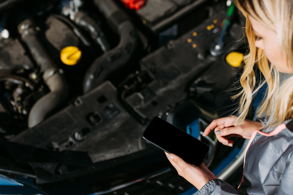 Kırpılan atış smartphone ile boş ekran kırık araba tamir ederken kullanan kız  - Fotoğraf, Görsel