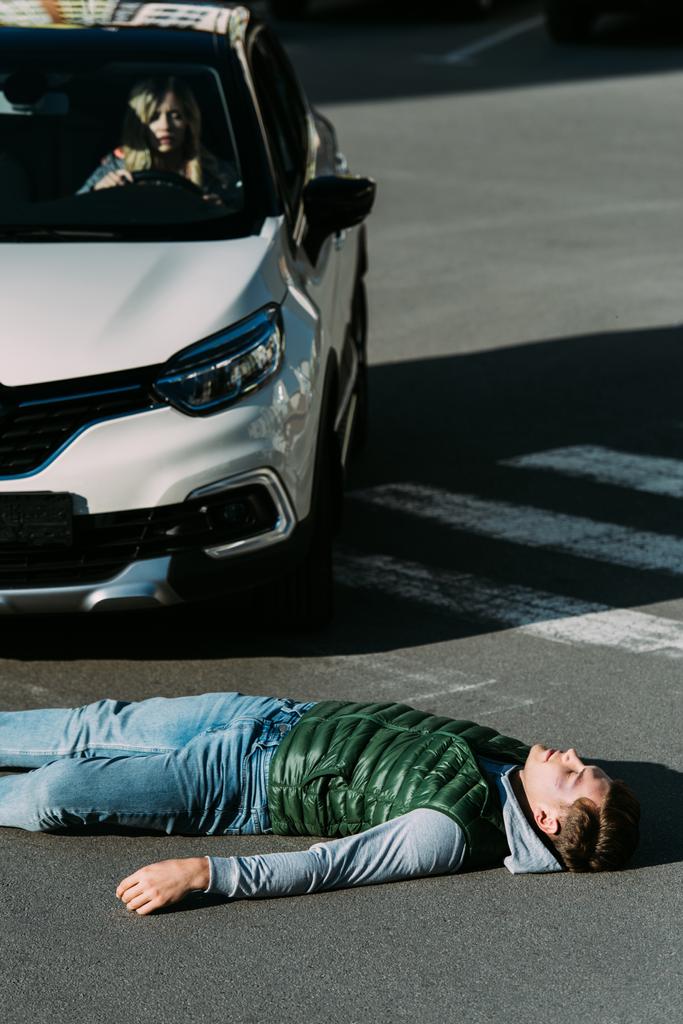 высокий угол обзора раненого молодого человека, лежащего на дороге после ДТП
 - Фото, изображение