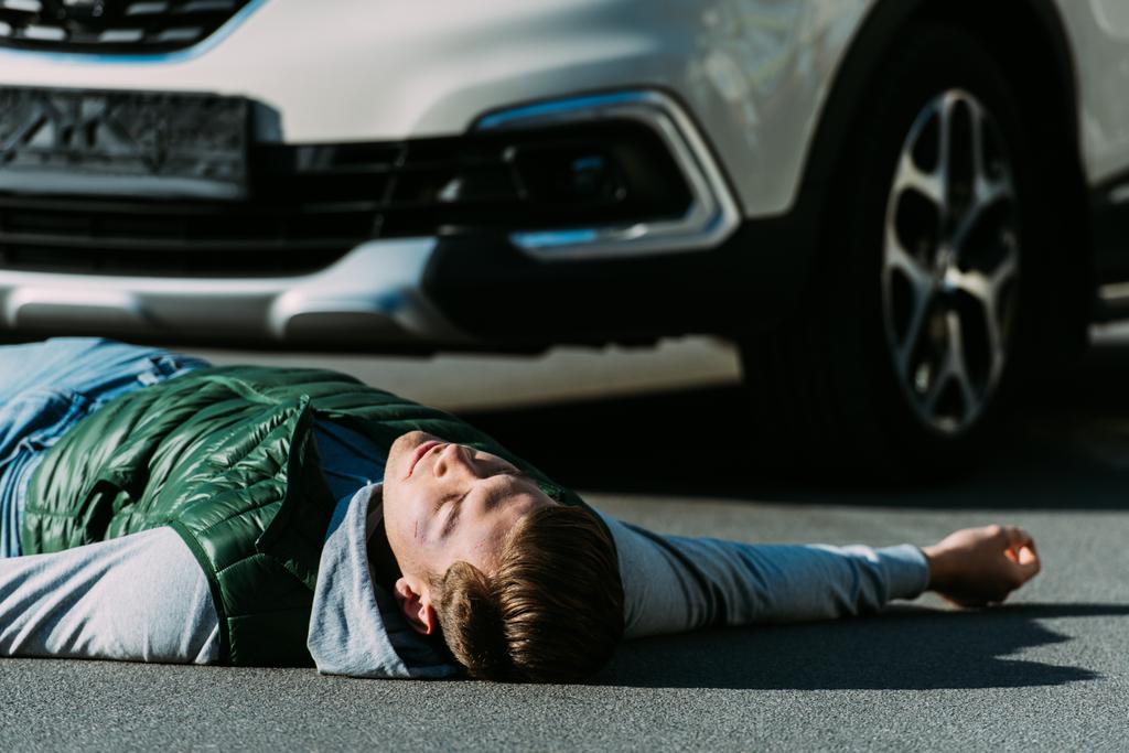 Крупный план раненого молодого человека, лежащего на дороге после ДТП
 - Фото, изображение