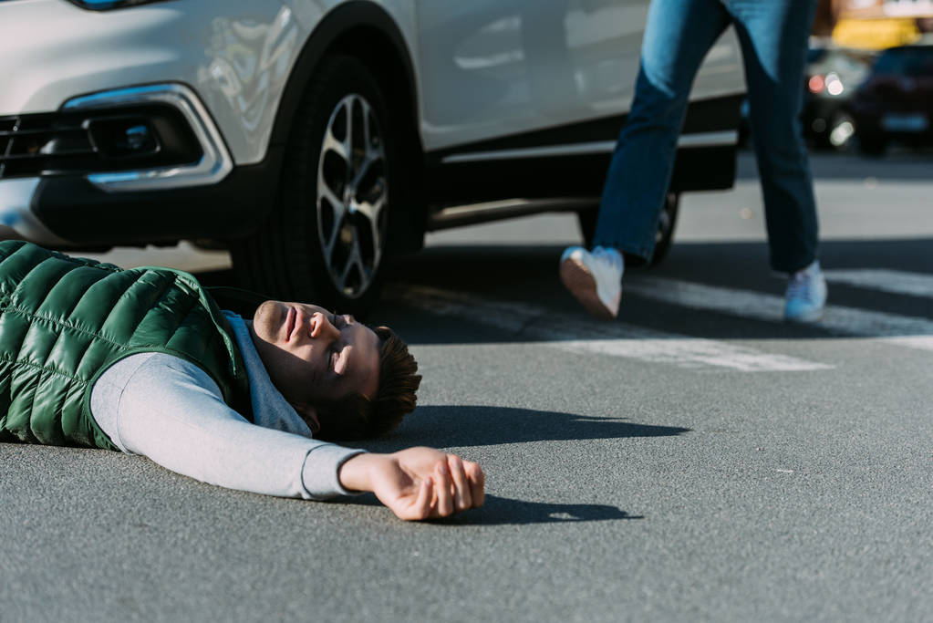 rajattu kuva naisesta, joka juoksee auto-onnettomuuden uhriin makaamassa tiellä
 - Valokuva, kuva
