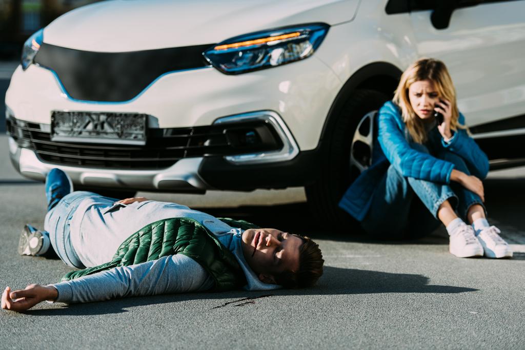 若い女性間の自動車衝突の後道路に横たわっている負傷の男性緊急の呼び出し - 写真・画像