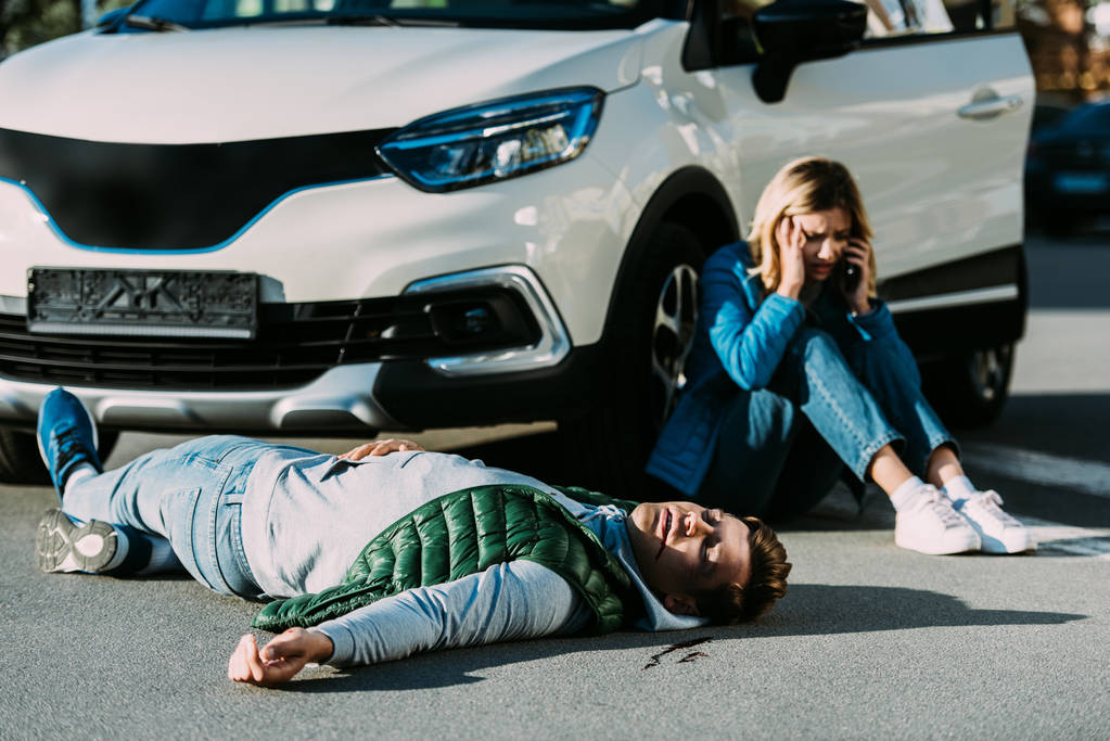 effrayé jeune femme appelant d'urgence tandis que l'homme blessé couché sur la route après collision de la circulation
  - Photo, image