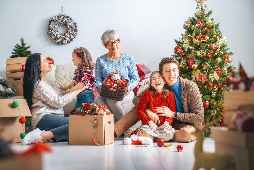 メリー クリスマスとハッピー ホリデー!おばあちゃん、母親、父親と子供たちは、部屋にツリーを飾る。愛情のある家族の室内. - 写真・画像