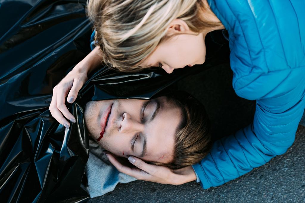 若い女性と道路で死んだ男を抱いて泣きのクローズ アップ ビュー  - 写真・画像
