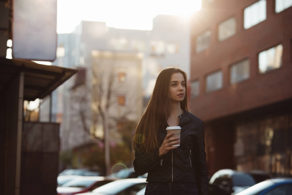 Bella donna in possesso di tazza di caffè di carta e godendo di una passeggiata in città
 - Foto, immagini