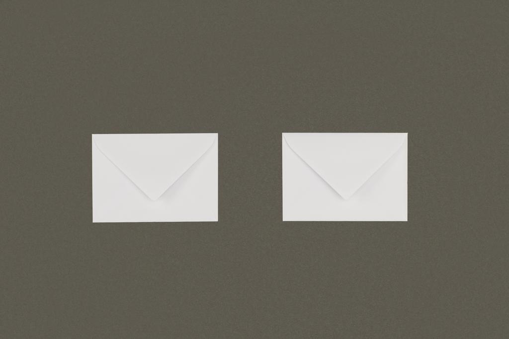 vista de perto de dois envelopes brancos dispostos isolados sobre fundo cinzento
 - Foto, Imagem