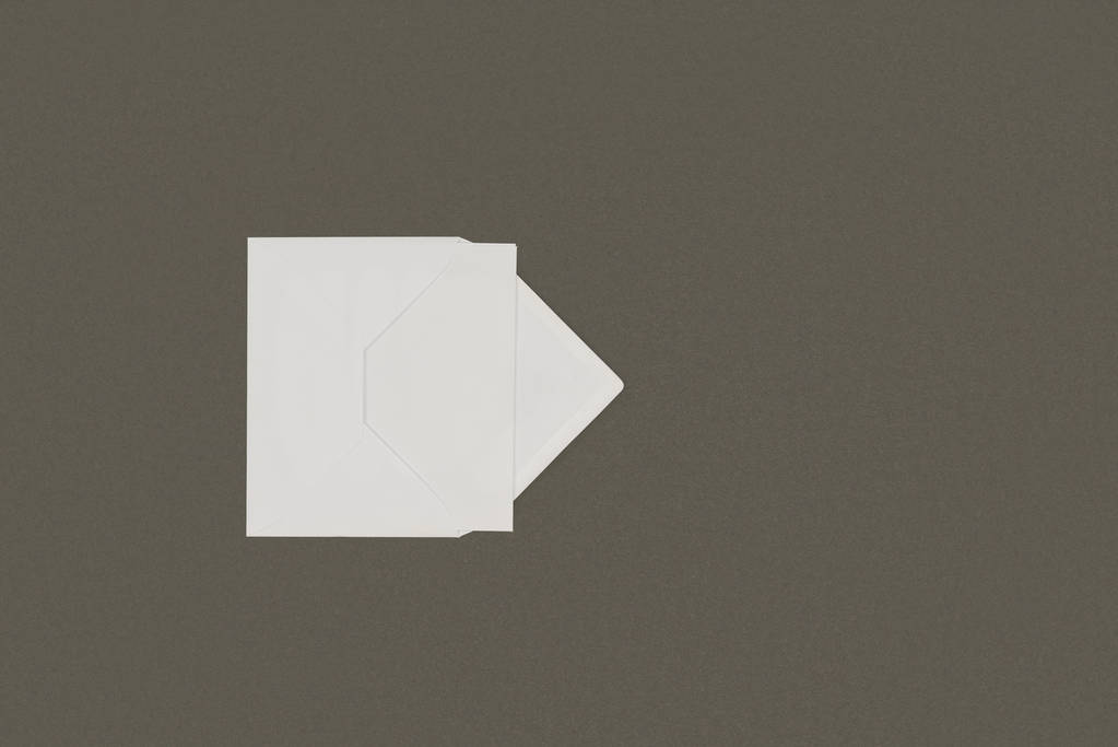 灰色の背景に分離された空白のカードを開いて白い封筒の上から見る - 写真・画像