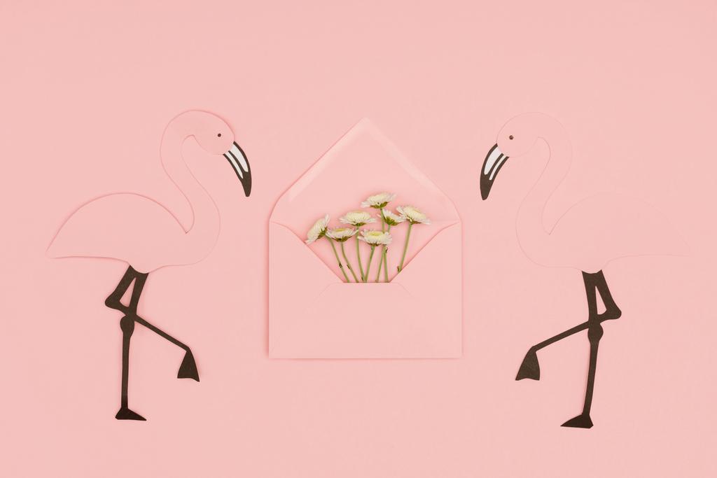 Detailní pohled otevřených růžové obálky s malými bílými květy a plameňáci papercut izolované na růžové - Fotografie, Obrázek